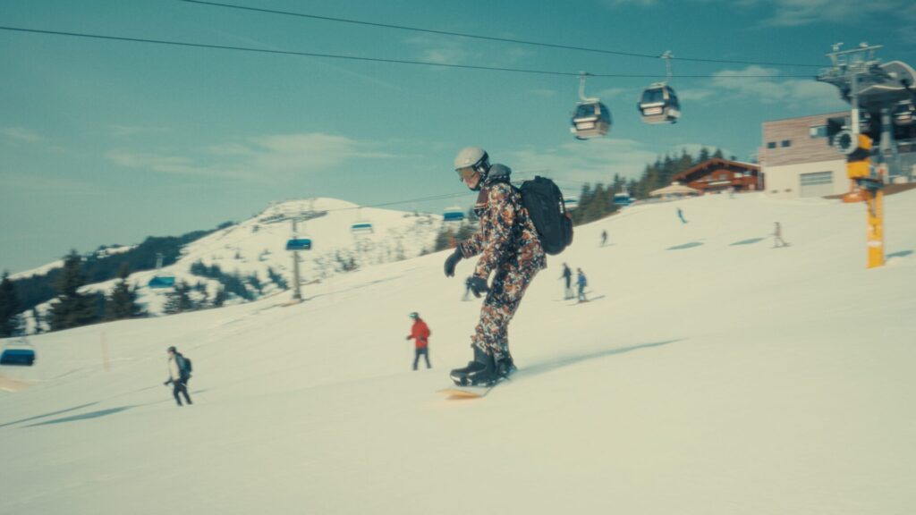 Snowboarder op een zonnige piste met gondels
