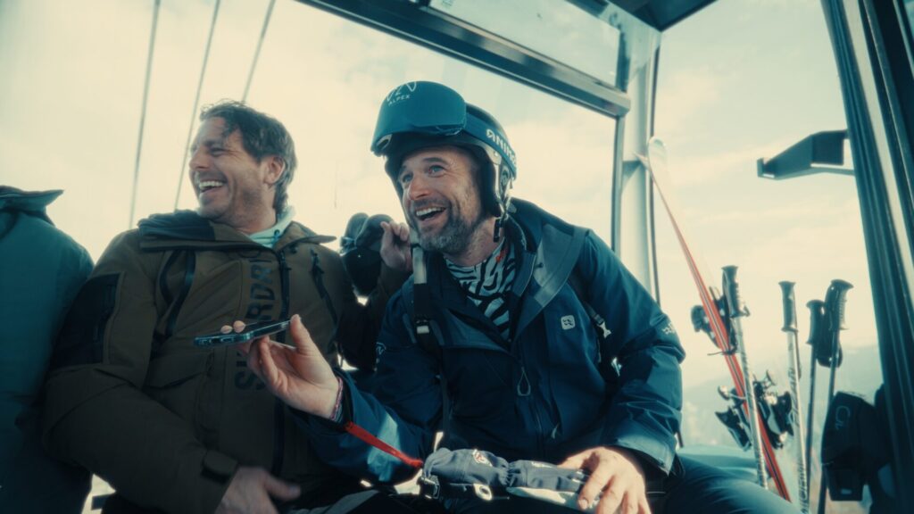 Twee deelnemers lachen in een cabine boven de bergen