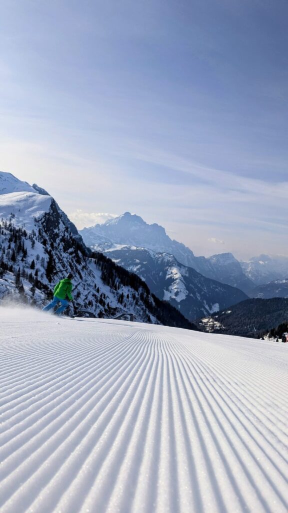 Skiër op een vers geprepareerde piste met uitzicht over de Dolomieten